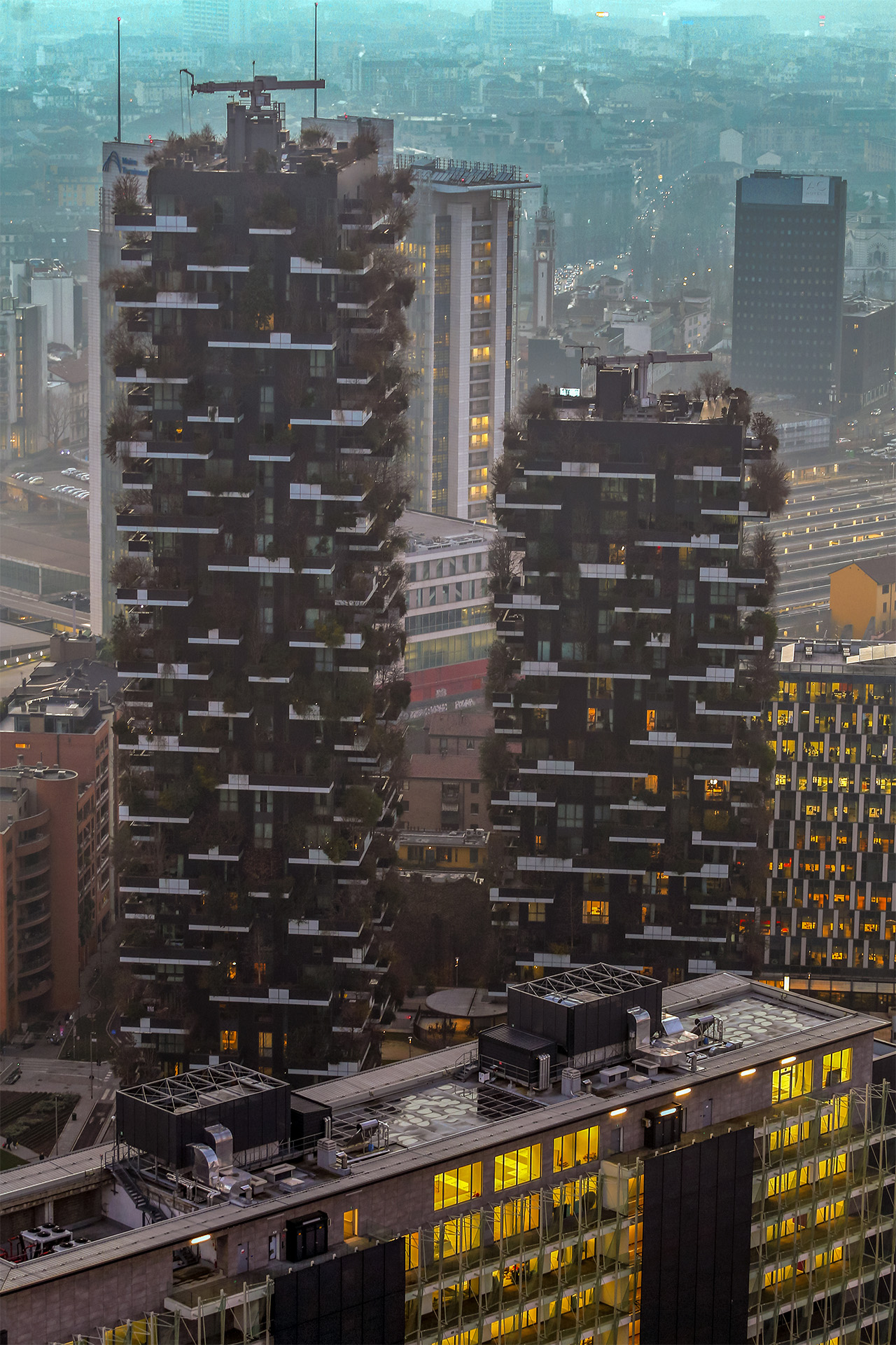 Il Bosco Verticale in inverno, rami spogli, atmosfera nebbiosa al crepuscolo.