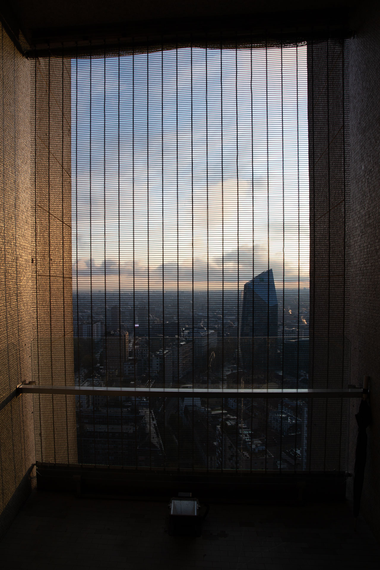 Vista dall'interno del Pirellone attraverso le lamelle della facciata, verso la Torre BNP Paribas al tramonto.