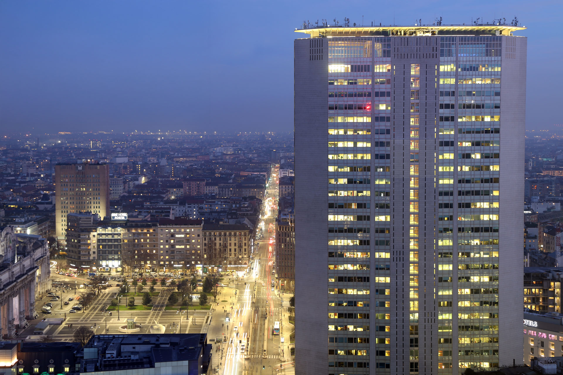 Il Grattacielo Pirelli al blue hour, con Piazza Duca d'Aosta e Via Vittor Pisani illuminate.