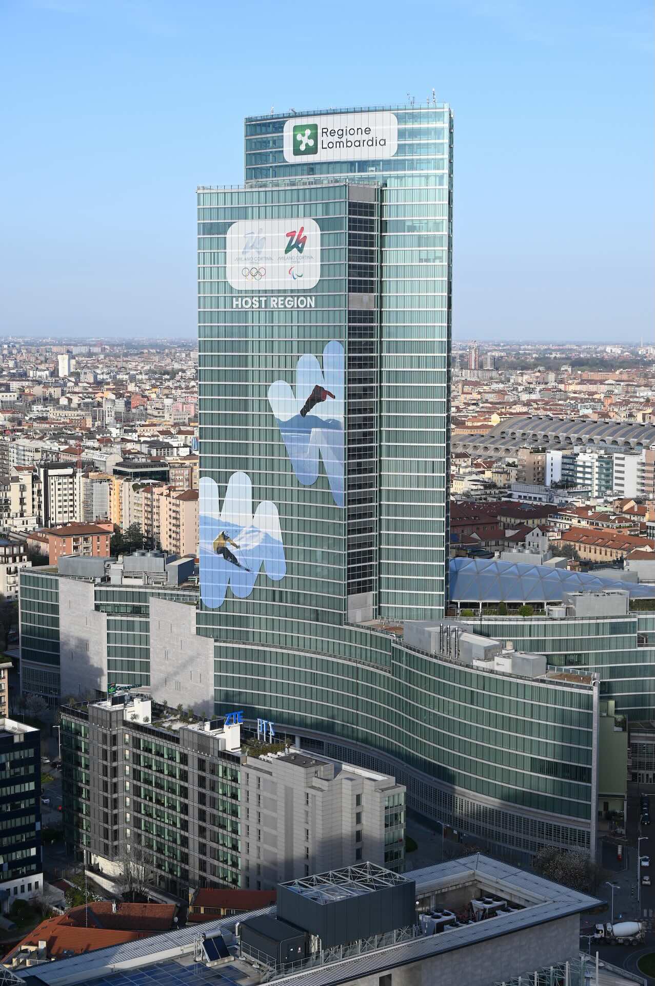 Ripresa aerea ravvicinata della torre con i banner delle Olimpiadi Milano-Cortina 2026.