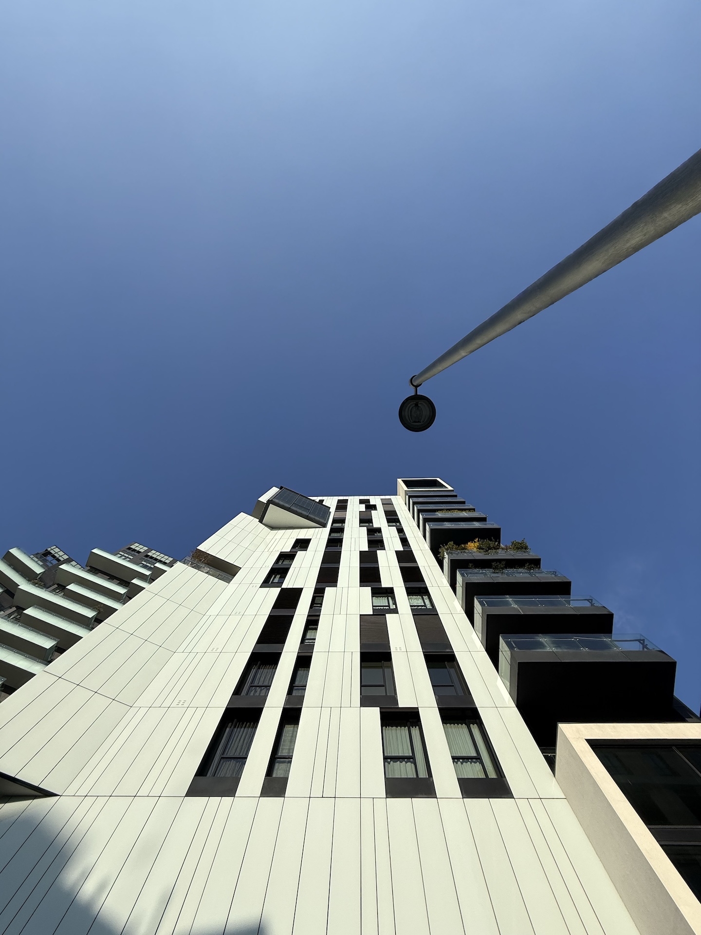La Torre Aria vista dal basso contro un cielo blu intenso, con un lampione in primo piano.