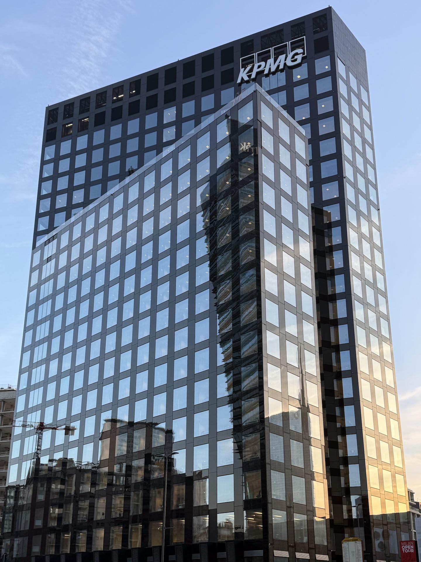 La sommità della Torre Est con il logo KPMG, in controluce al tramonto.