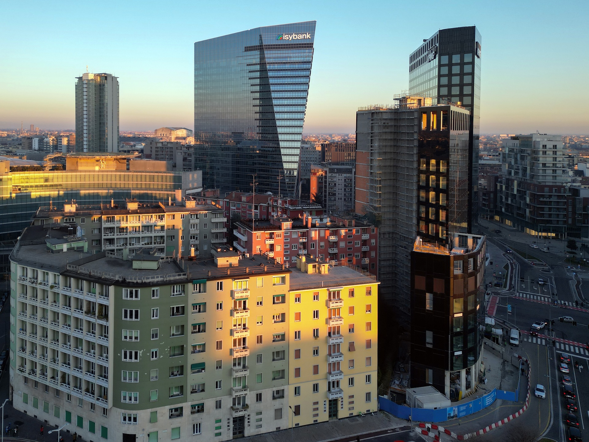 La Torre Gioia 22 al tramonto, tra i palazzi residenziali colorati del quartiere e una torre in costruzione.
