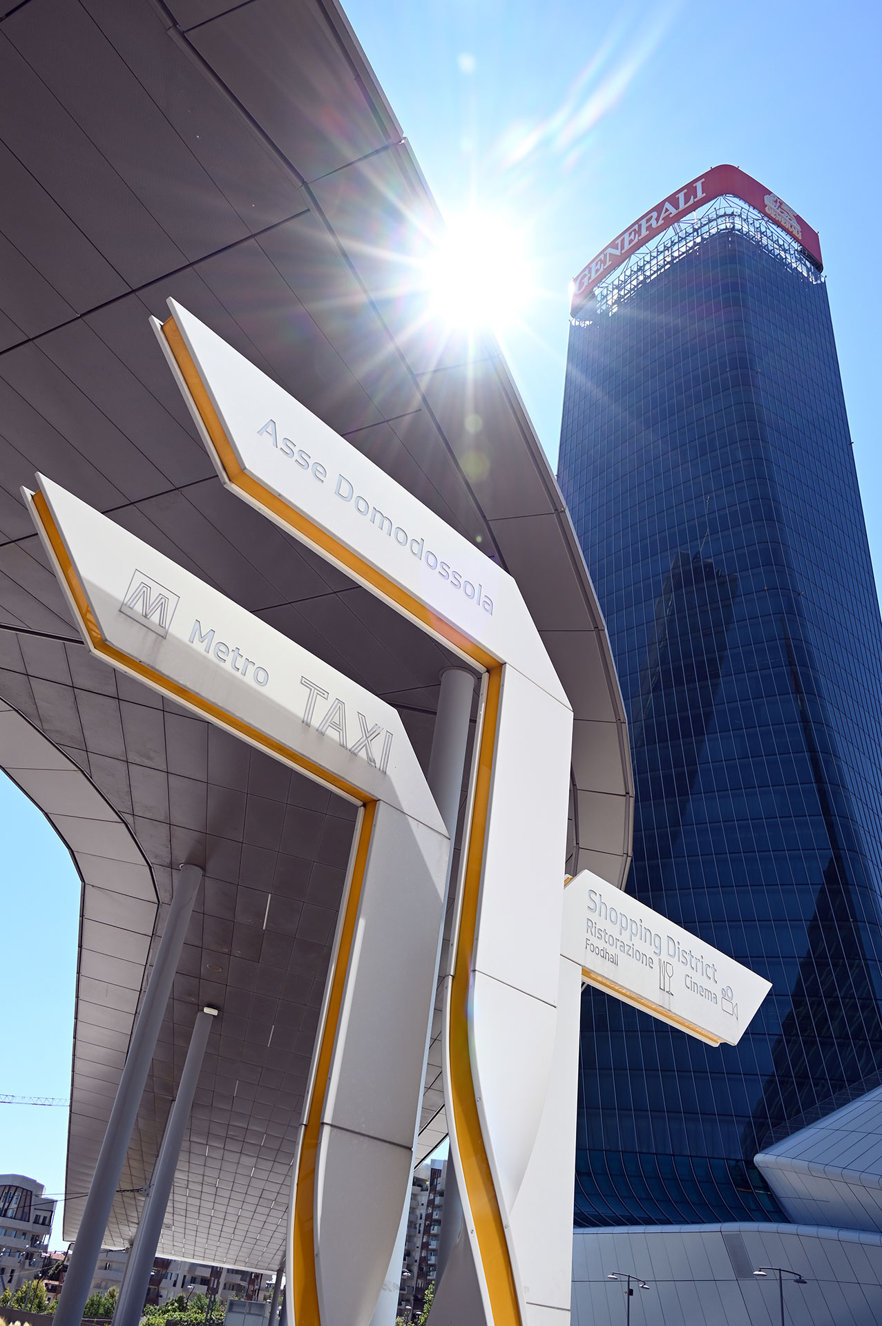 Cartello di indicazione della fermata M5 Tre Torri, con la Torre Hadid sullo sfondo in controluce.