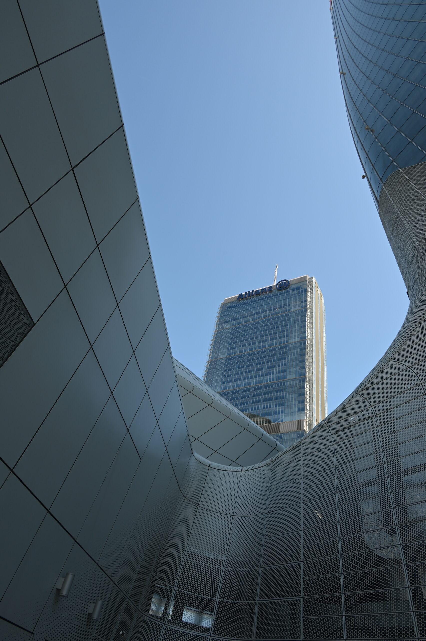La Torre Isozaki vista dal basso tra le architetture curve di CityLife, contro un cielo blu terso.