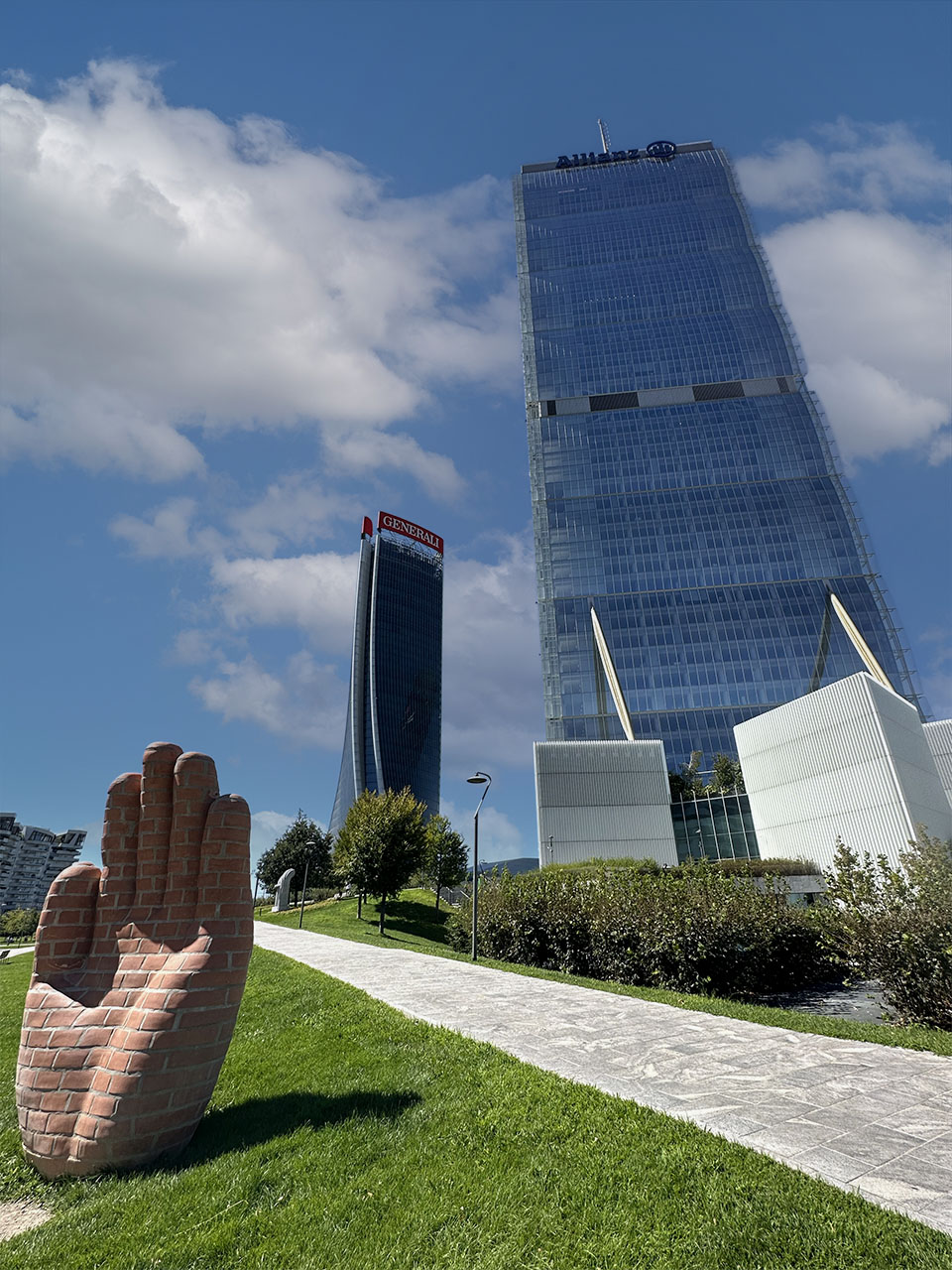 La scultura 'La Mano' di Lorenzo Quinn nel parco di CityLife, con la Torre Isozaki e la Torre Generali sullo sfondo.