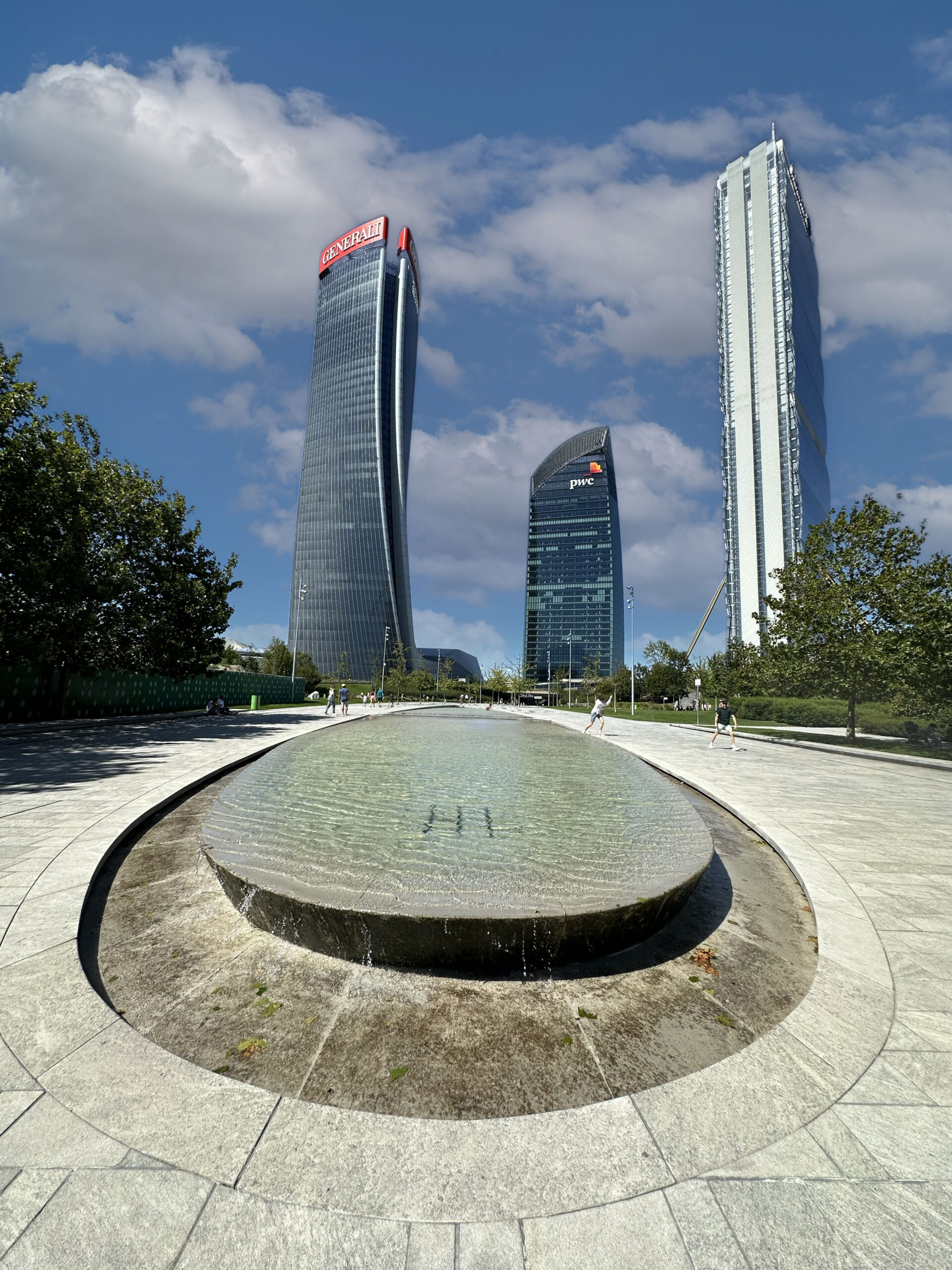 Vista grandangolare della fontana di Piazza Tre Torri con le Tre Torri di CityLife sullo sfondo.