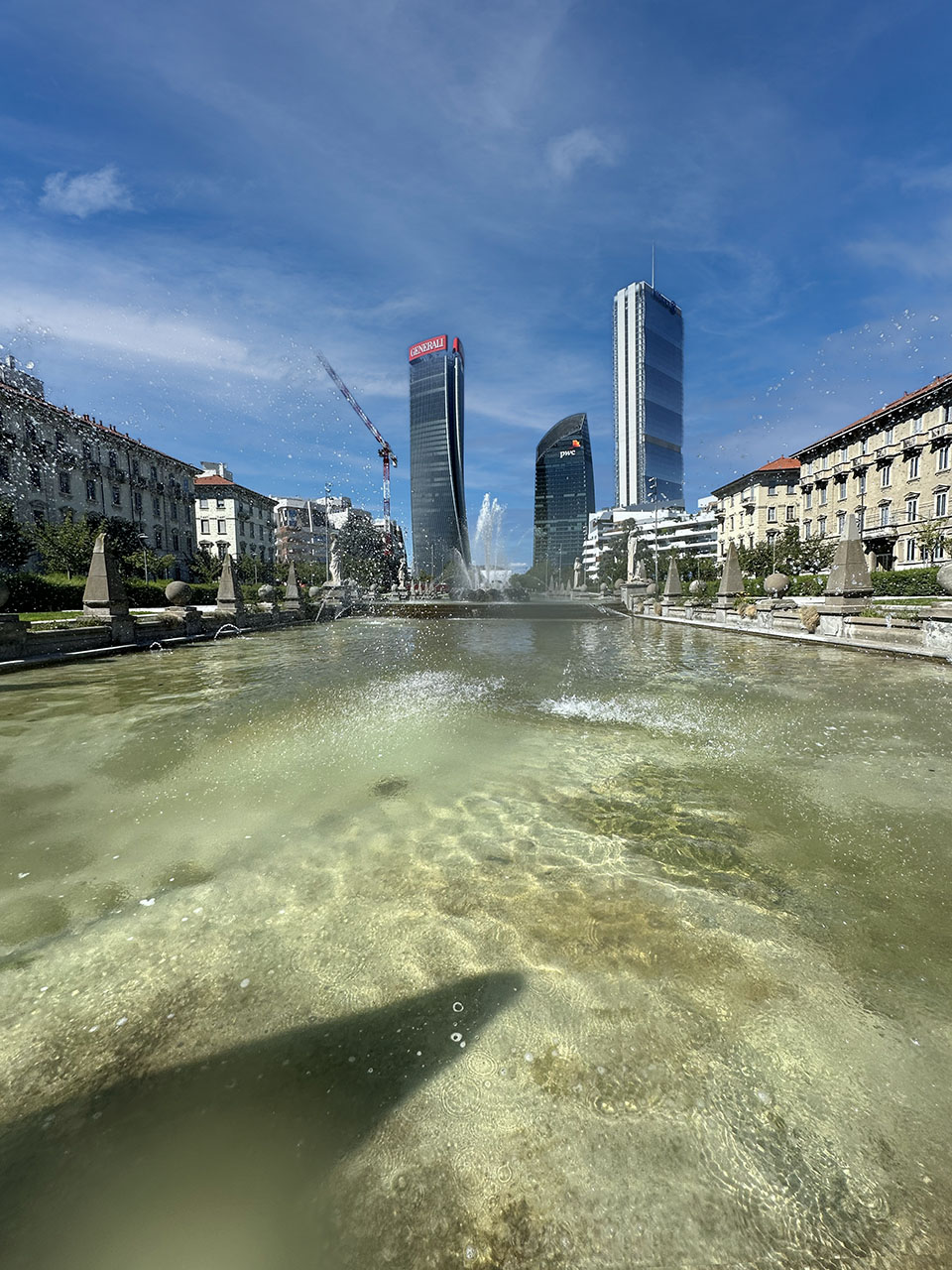Lo skyline di CityLife visto dalla fontana storica di Piazza Castello, tra edifici d'epoca milanesi.