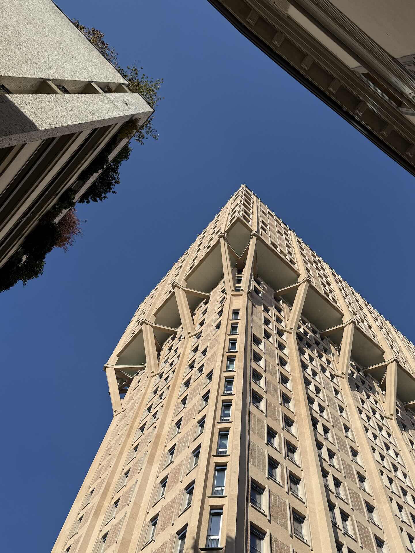 La Torre Velasca vista dal basso in diagonale, con il profilo a fungo e le mensole ben visibili.