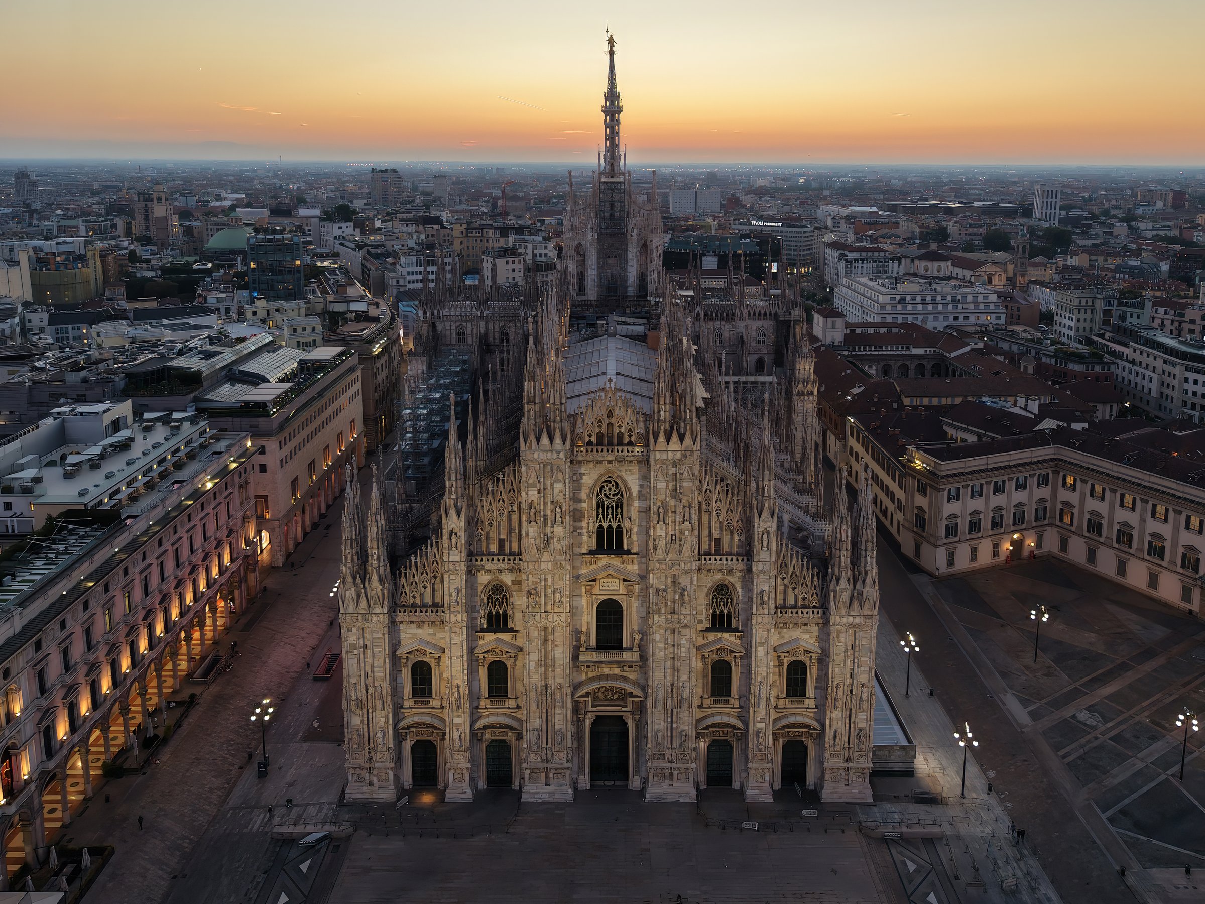 Il Duomo di Milano e i suoi pinnacoli ripresi dal drone, con la città sullo sfondo all'alba.