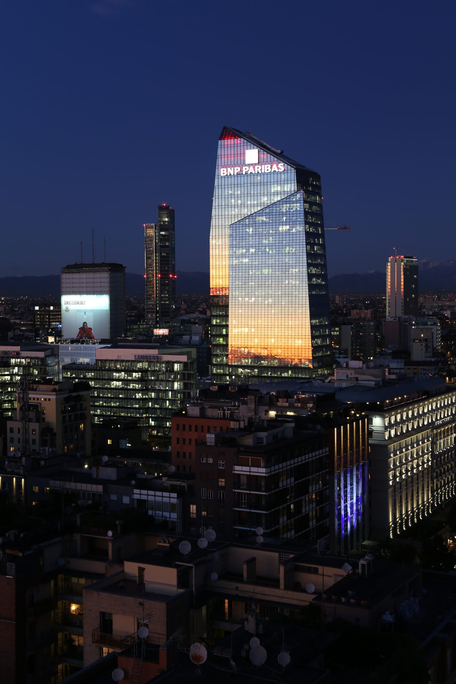 La Torre Diamante di notte tra i grattacieli di Porta Nuova, con la Torre Solaria e le Alpi sullo sfondo.